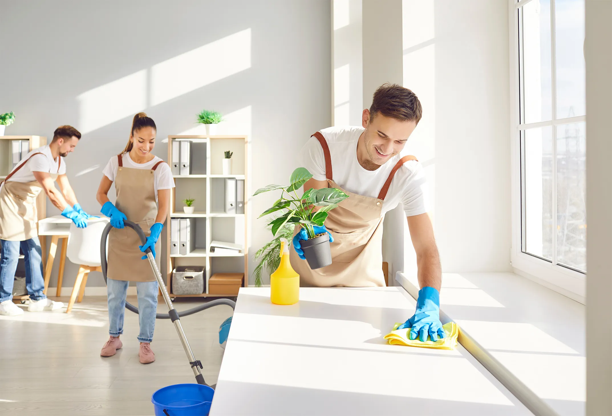 Male top performing cleaner and happy team cleaning room. Group sanitizing home, dust surface, vacuum and mop floors and clean house windows
