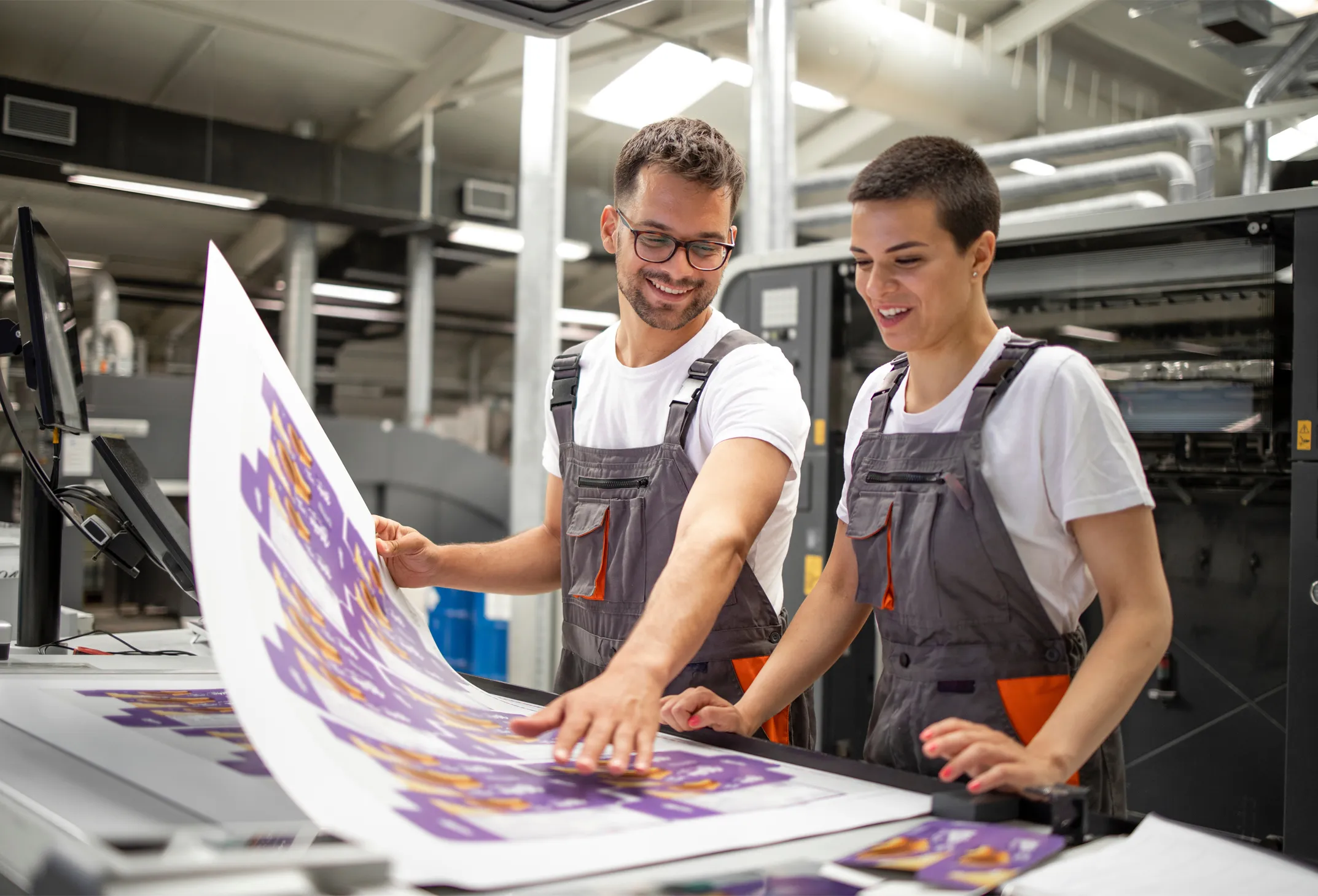 Graphic engineers or workers checking imprint quality in modern print shop.